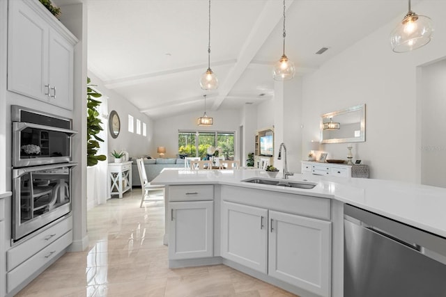 kitchen with sink, vaulted ceiling with beams, pendant lighting, white cabinets, and appliances with stainless steel finishes