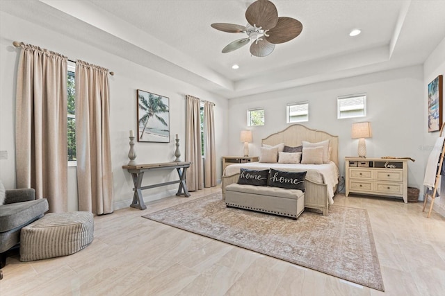 bedroom featuring multiple windows, a raised ceiling, and ceiling fan