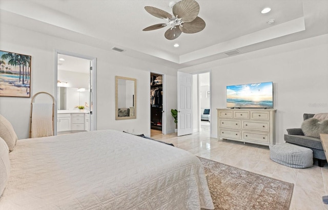 bedroom with ensuite bath, a spacious closet, ceiling fan, a raised ceiling, and a closet