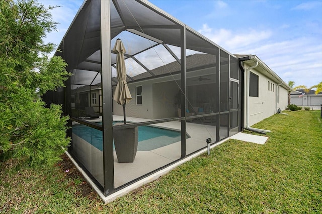 back of house with glass enclosure, a patio area, and a lawn