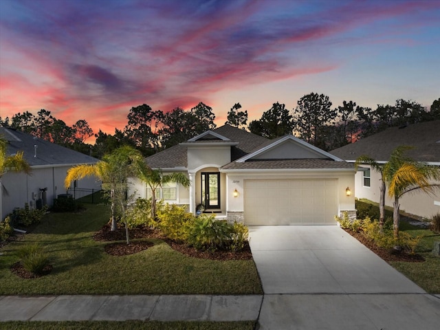 ranch-style home featuring a garage, driveway, stucco siding, and a yard