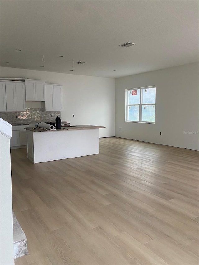 kitchen featuring light wood-type flooring, white cabinetry, tasteful backsplash, and a kitchen island