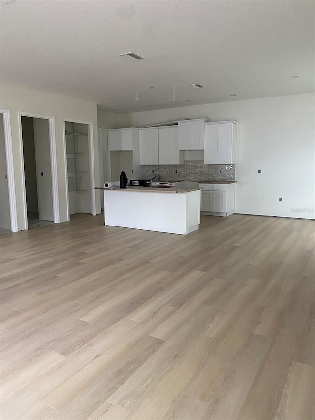 kitchen featuring decorative backsplash, white cabinetry, light hardwood / wood-style flooring, and a kitchen island