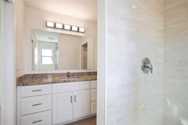 bathroom featuring a tile shower and vanity