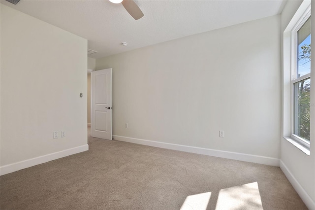 spare room with baseboards, plenty of natural light, and light colored carpet