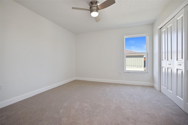 unfurnished bedroom with a textured ceiling, baseboards, a closet, and light colored carpet