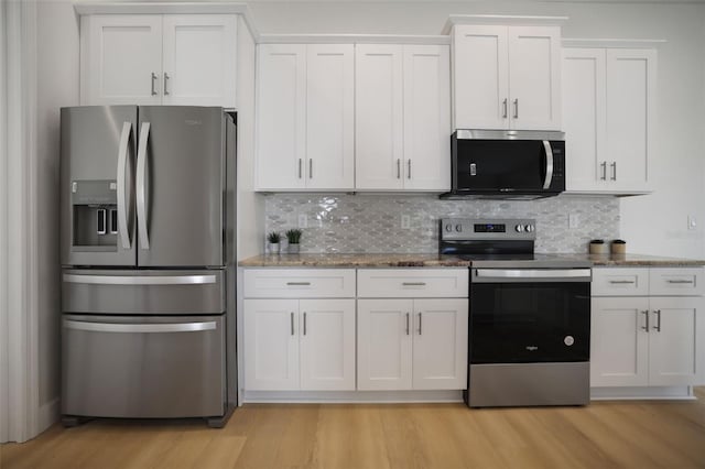 kitchen with appliances with stainless steel finishes, stone counters, light wood-type flooring, and backsplash