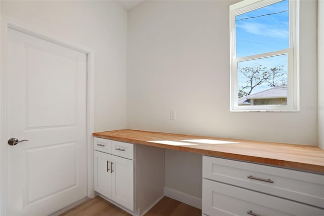 unfurnished office with light wood-type flooring and built in desk