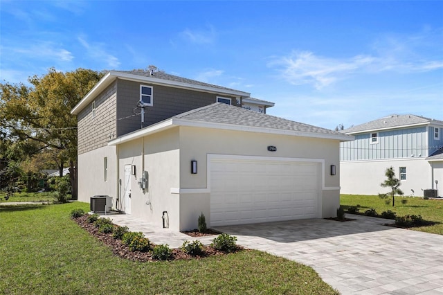 view of front of property with a garage, a front lawn, central AC, and stucco siding