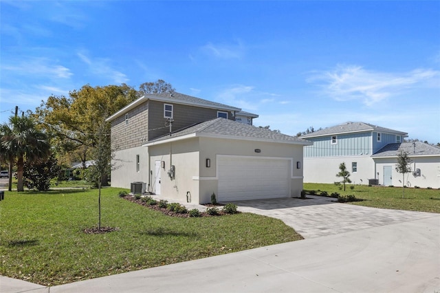 traditional home featuring an attached garage, a shingled roof, decorative driveway, stucco siding, and a front yard