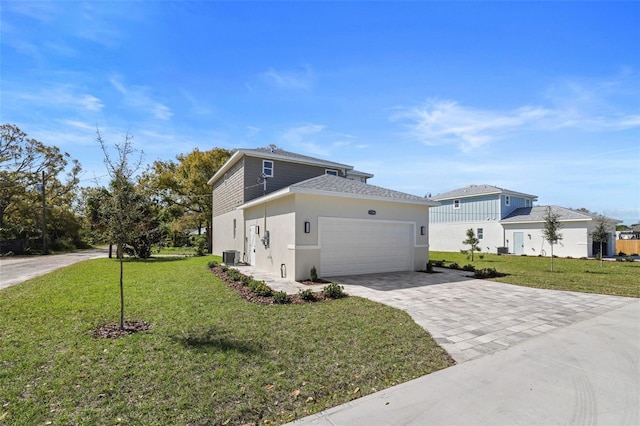 view of front of home featuring a front lawn, decorative driveway, an attached garage, and central air condition unit