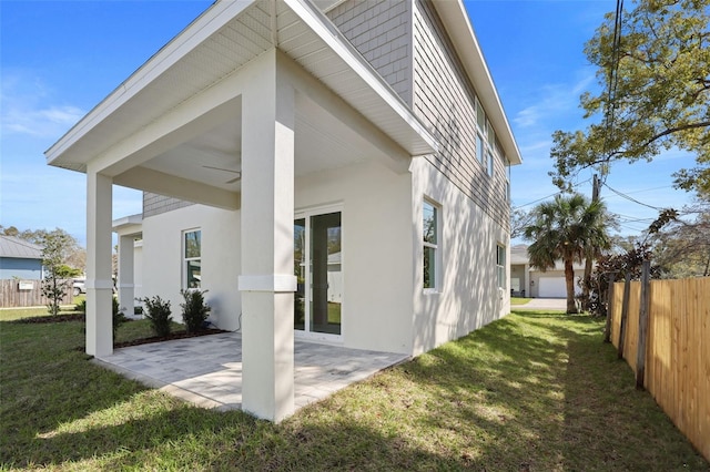 back of property with stucco siding, a lawn, a patio, and fence