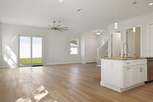 kitchen featuring light wood-style flooring, baseboards, a sink, and decorative light fixtures