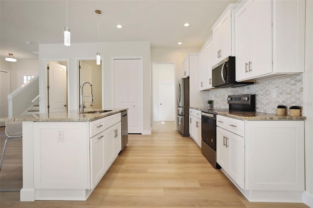 kitchen with stainless steel appliances, decorative backsplash, white cabinetry, a sink, and a kitchen breakfast bar