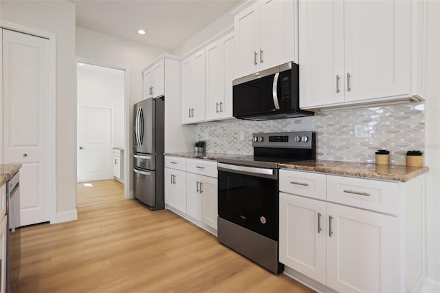 kitchen featuring stone counters, tasteful backsplash, appliances with stainless steel finishes, light wood-style floors, and white cabinetry