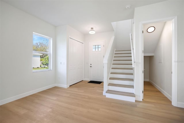 foyer featuring baseboards, light wood-type flooring, and a healthy amount of sunlight