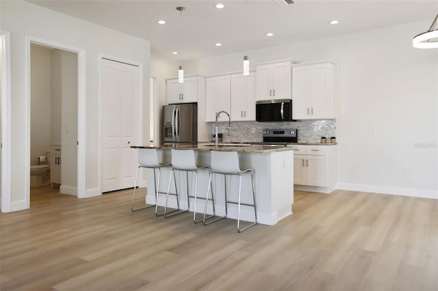 kitchen featuring a breakfast bar, a center island with sink, stainless steel appliances, tasteful backsplash, and a sink