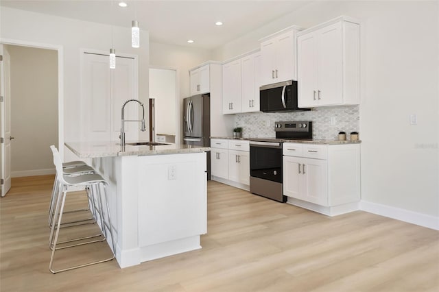 kitchen with backsplash, white cabinetry, stainless steel appliances, and a sink