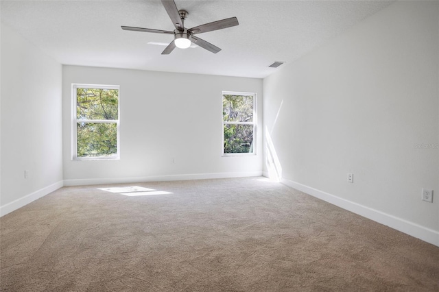 unfurnished room featuring carpet floors, baseboards, visible vents, and a wealth of natural light