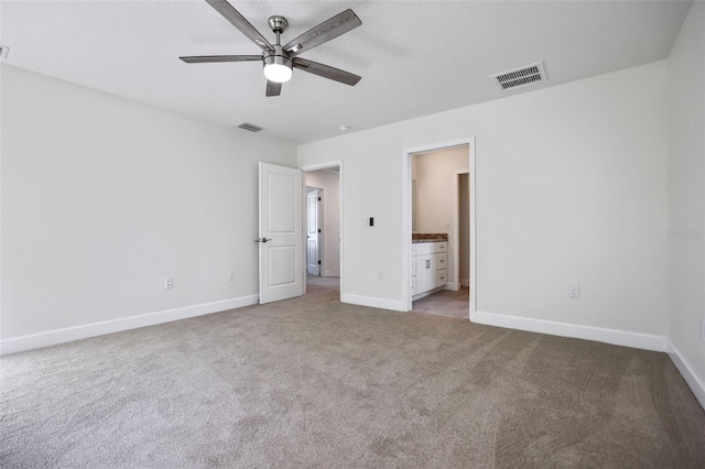 unfurnished bedroom featuring ensuite bath, carpet flooring, visible vents, and baseboards