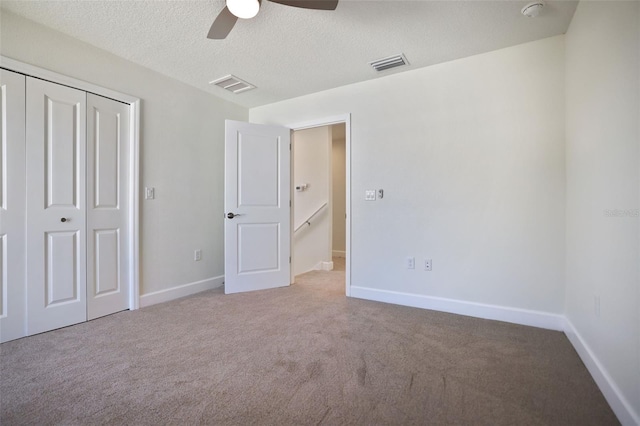 unfurnished bedroom featuring a textured ceiling, carpet floors, visible vents, and baseboards