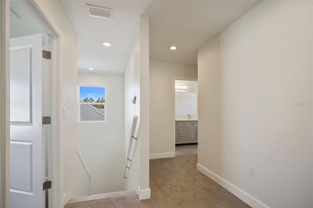 hall with recessed lighting, light carpet, visible vents, an upstairs landing, and baseboards