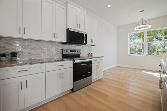 kitchen with light wood-style floors, appliances with stainless steel finishes, white cabinets, and backsplash