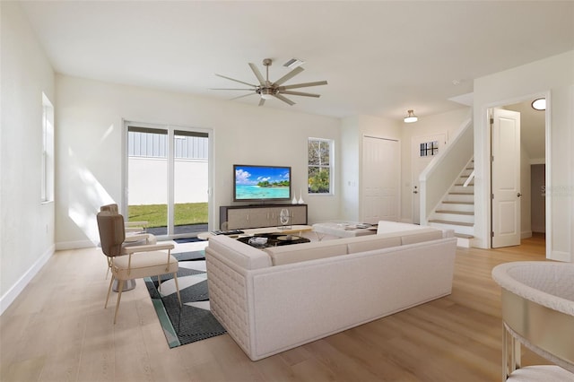 living area with stairway, light wood-type flooring, visible vents, and baseboards