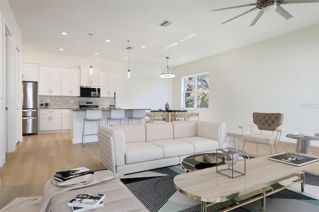 living room with light wood finished floors, visible vents, baseboards, ceiling fan, and recessed lighting