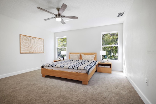 bedroom with baseboards, a textured ceiling, visible vents, and carpet flooring