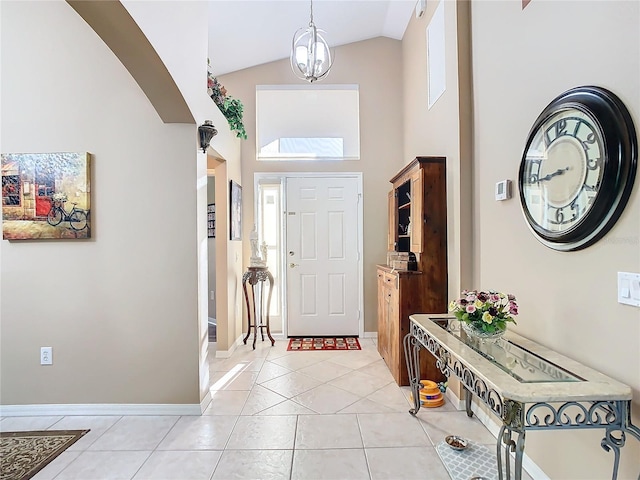 foyer entrance featuring light tile patterned floors, lofted ceiling, and a notable chandelier