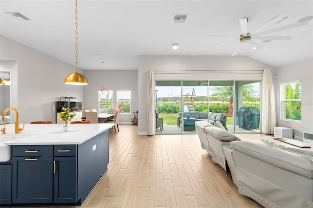 kitchen with a wealth of natural light, pendant lighting, ceiling fan with notable chandelier, and blue cabinets