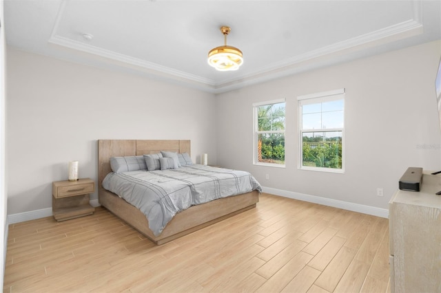 bedroom featuring a raised ceiling, ornamental molding, and light wood-type flooring