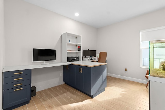 home office featuring light hardwood / wood-style floors and built in desk