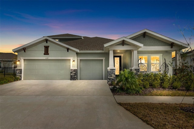 craftsman inspired home featuring concrete driveway, an attached garage, roof with shingles, and stucco siding