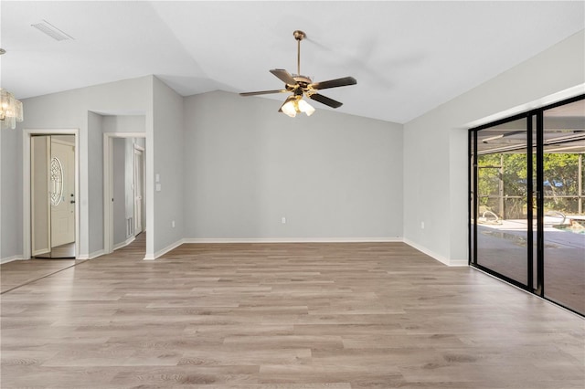 empty room with light hardwood / wood-style flooring, ceiling fan with notable chandelier, and lofted ceiling