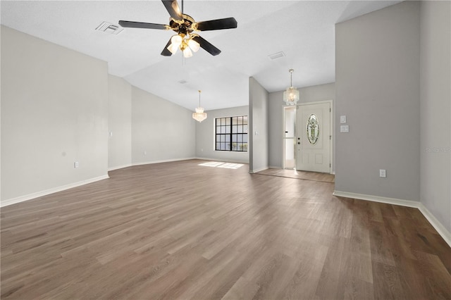 unfurnished living room with hardwood / wood-style floors, ceiling fan with notable chandelier, and vaulted ceiling