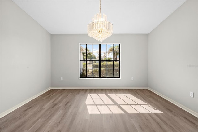 unfurnished room featuring hardwood / wood-style flooring and an inviting chandelier