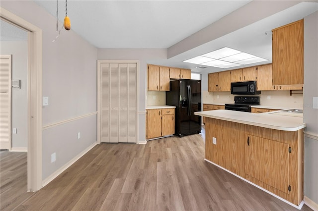 kitchen featuring kitchen peninsula, light wood-type flooring, sink, and black appliances