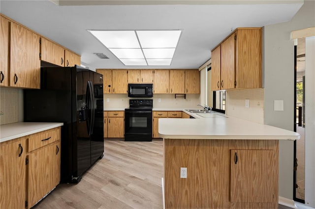 kitchen with sink, light hardwood / wood-style flooring, backsplash, kitchen peninsula, and black appliances