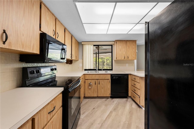 kitchen featuring black appliances, light wood-type flooring, and sink