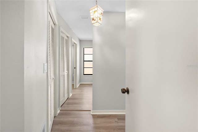 hallway with light hardwood / wood-style flooring and an inviting chandelier