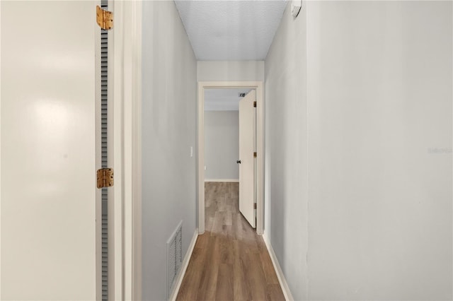 hall featuring wood-type flooring and a textured ceiling