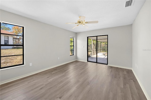 empty room with ceiling fan, wood-type flooring, and a textured ceiling