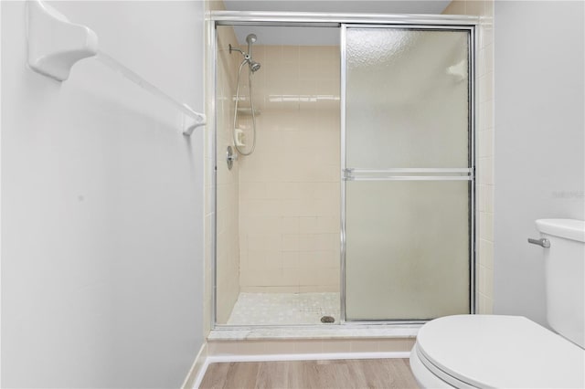 bathroom with wood-type flooring, toilet, and an enclosed shower