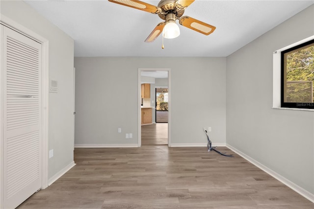 empty room with ceiling fan and light hardwood / wood-style flooring