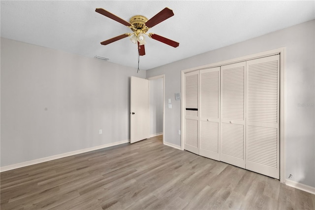 unfurnished bedroom featuring ceiling fan, light hardwood / wood-style floors, and a closet