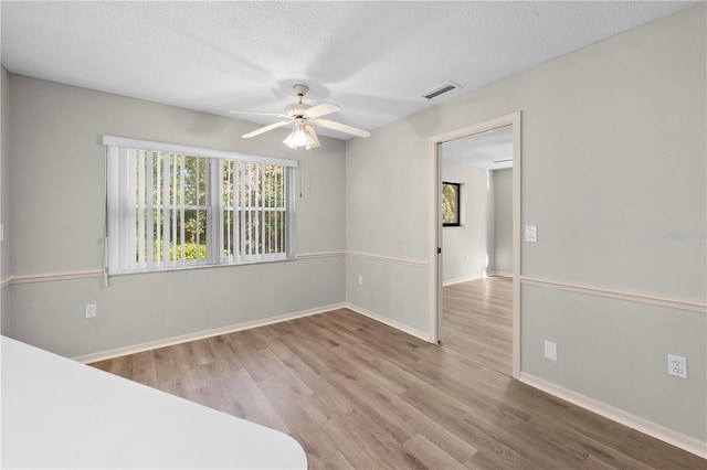 unfurnished bedroom with a textured ceiling, light hardwood / wood-style flooring, and ceiling fan