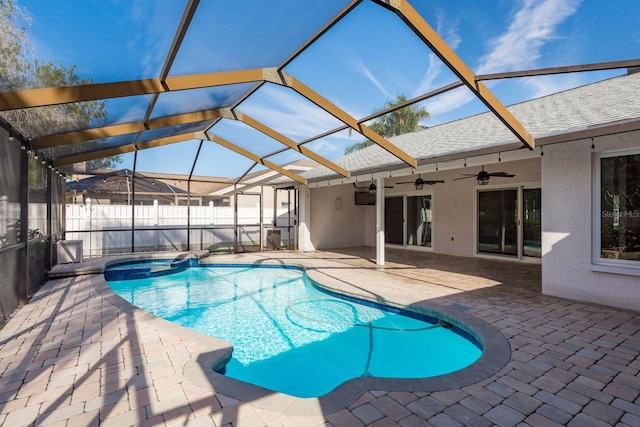 view of swimming pool with ceiling fan, an in ground hot tub, glass enclosure, and a patio