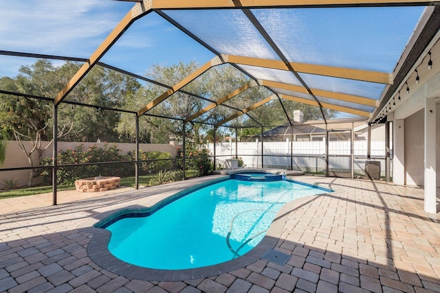 view of pool with glass enclosure, a patio area, and an in ground hot tub